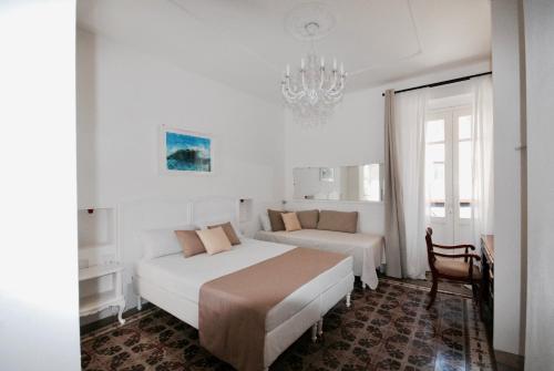 a hotel room with two beds and a chandelier at Su Zampillu Boutique Rooms Teulada in Teulada