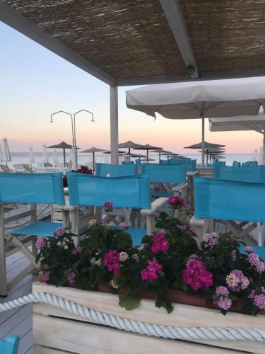 a group of blue tables and chairs on a deck with flowers at Makedos Sea View in Nea Vrasna