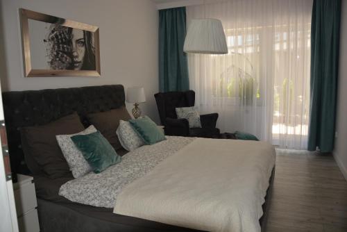 a bedroom with a large bed and a chair at Apartament na Leśnej in Pobierowo