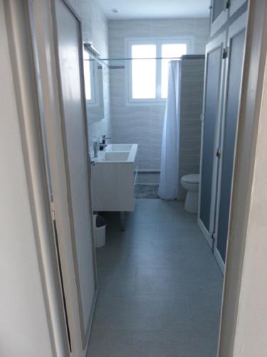 une salle de bain blanche avec un lavabo et des toilettes dans l'établissement Maison Chez Nous, à Royan