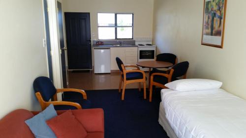 a small room with a bed and a table and chairs at The Peaks Motor Inn in Ohakune