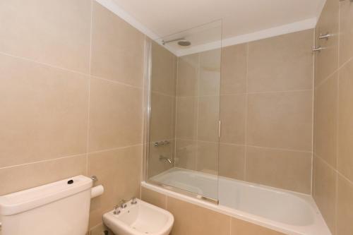 a bathroom with a shower and a toilet and a tub at Austral Departamentos in Ushuaia