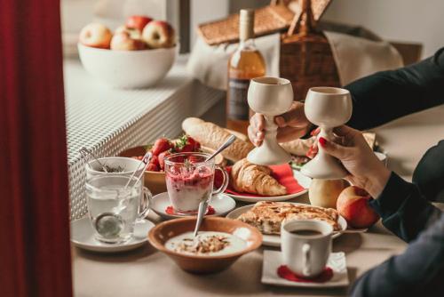 two people sitting at a breakfast table with food at Rooms & Apartments Podsreda Castle in Podsreda