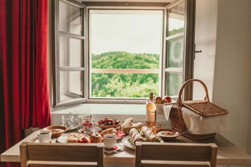 a table with a plate of food in front of a window at Rooms & Apartments Podsreda Castle in Podsreda