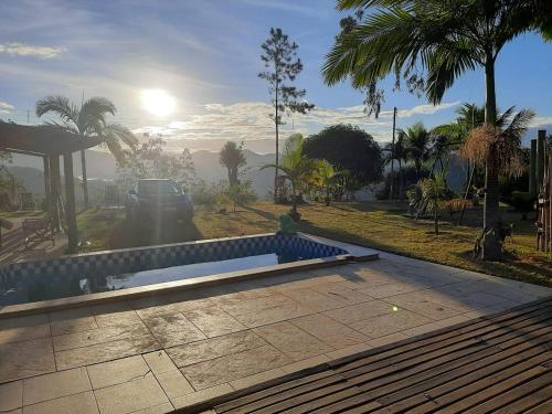 a pool in a park with the sun in the background at Pousada Sítio Rústicu's in Domingos Martins