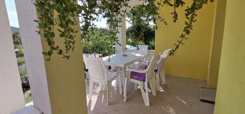 a white table and white chairs on a patio at Anđela Home - Krka waterfalls in Lozovac