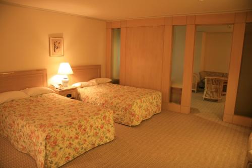a hotel room with two beds and a lamp at Kyu Karuizawa Hotel Otowa No Mori in Karuizawa