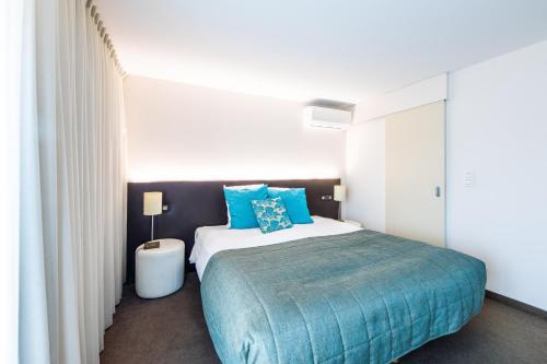 a bedroom with a large bed with blue pillows at Hotel Malpertuus in Riemst