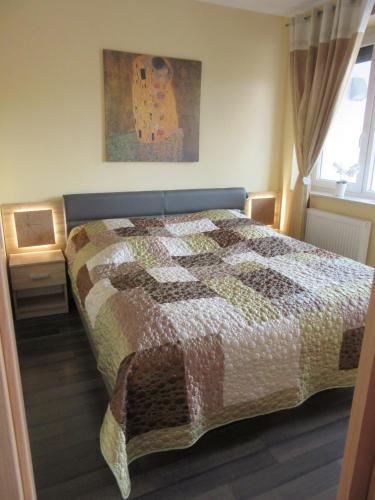 Un dormitorio con una cama con una colcha encima en Zafír Sziget Apartman, en Sárvár