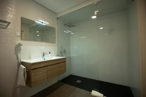 a bathroom with a sink and a glass shower at Refúgio do Avô - Vale de Lourinhã in Lourinhã