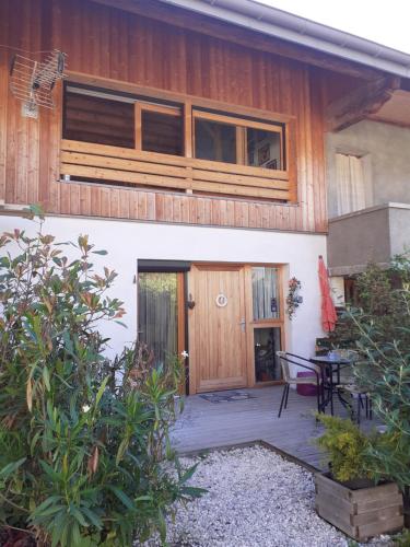 une maison avec une porte en bois et une terrasse dans l'établissement Lac et montagnes en un clin d'oeil, à Duingt