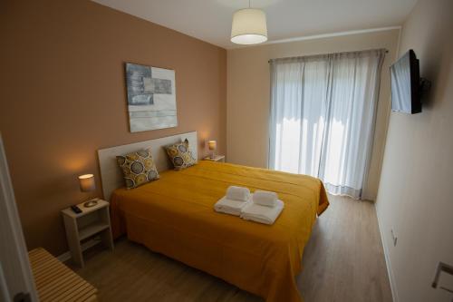um quarto com uma cama amarela com duas toalhas em Refúgio do Avô - Vale de Lourinhã na Lourinhã