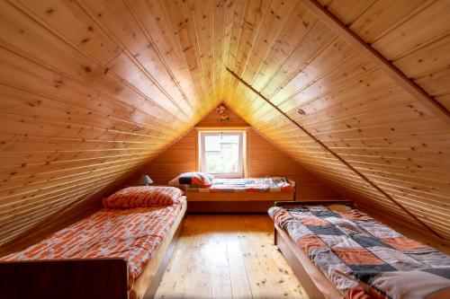 a room with two beds in a wooden attic at Studio Leśniakówka 693-664-683 in Ustrzyki Dolne