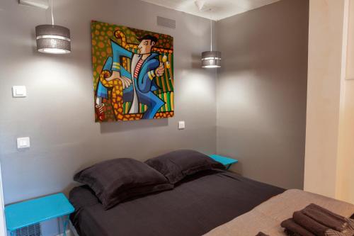 a bedroom with a bed with a painting on the wall at Les Terrasses Levantines in Île du Levant