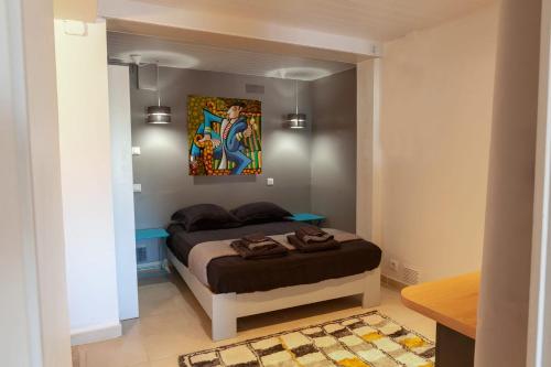 a bedroom with a bed and a painting on the wall at Les Terrasses Levantines in Île du Levant