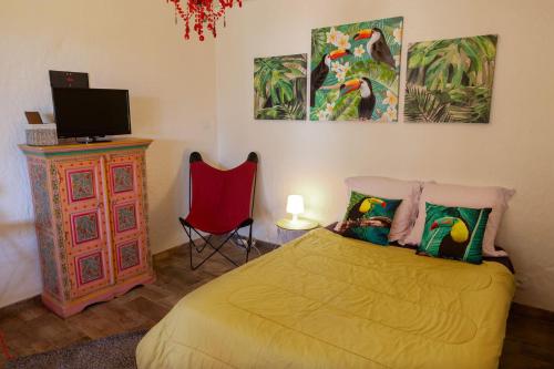 a bedroom with a bed and a tv and a red chair at Les Terrasses Levantines in Île du Levant