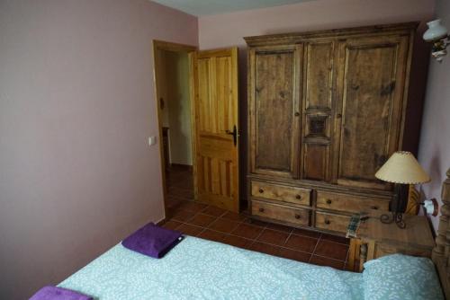 a bedroom with a bed and a wooden cabinet at La Puerta de Gredos in San Martín del Pimpollar