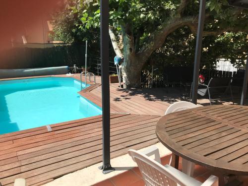 une terrasse en bois avec une table et une piscine dans l'établissement Chambre climatisée avec sdb privée dans une villa avec piscine ouverte d'avril à mi octobre, à Marseille