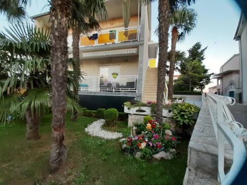 a house with palm trees and flowers in the yard at Apartment Dino in Selce