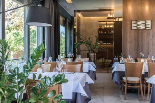 une salle à manger avec des tables blanches, des chaises et des plantes dans l'établissement Rooms & Restaurant Matanovi Dvori, à Sukošan