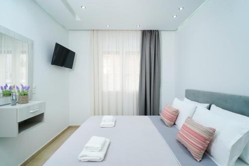 a white bedroom with a large white bed with pillows at Tarsa's House by the Sea in Skala Marion
