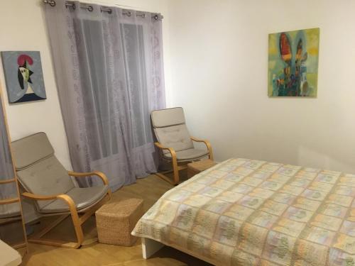 - une chambre avec deux chaises, un lit et une fenêtre dans l'établissement Des vacances de rêve, à Fréjus