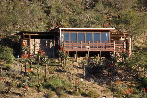 una casa al lado de una colina con árboles en Gourits River Guest Farm, en Albertinia