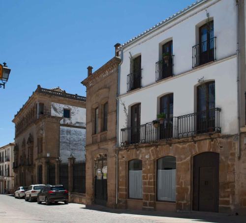 a group of buildings on a street with parked cars at Apartamentos Tres Llaves Palacio de Vela de los Cobos in Úbeda