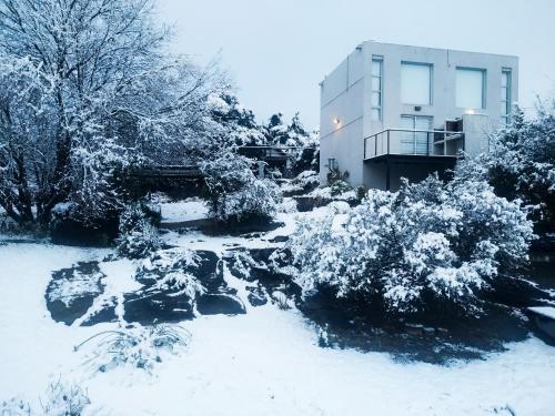 a garden covered in snow next to a building at Cabañas Paititi in Villa Carlos Paz