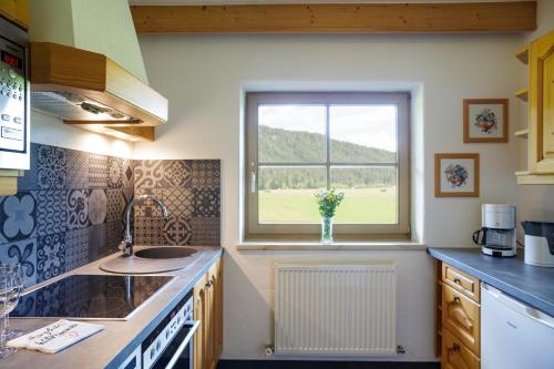 una cocina con una ventana con un jarrón de flores en Landhaus Lindl - Ein ruhiges Platzl zum Wohlfühlen, en Leutasch