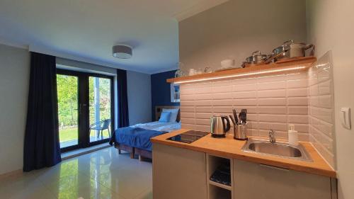a kitchen with a sink and a bedroom with a bed at Willa Abrazja - wypoczynek dla dorosłych in Jastrzębia Góra