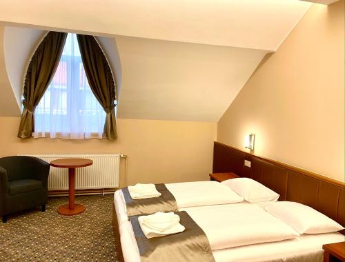 una stanza d'albergo con due letti e una sedia di Borostyán Panzió a Kaposvár