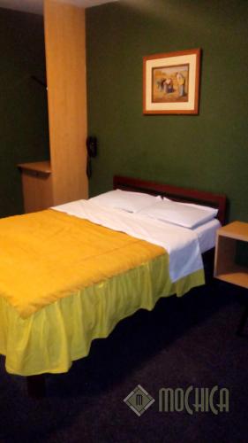 a hotel room with a bed with white and yellow sheets at Hostal Residencial Mochica in Lima