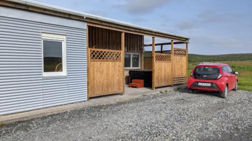 a red car parked in front of a building at Bjarnastaðir Guesthouse in Kópasker