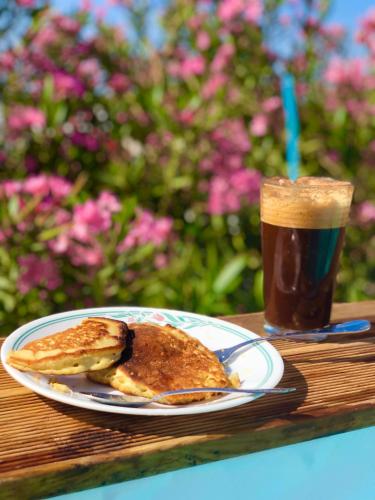 a plate of pancakes and a drink on a table at The Summer Pink House in Lachania