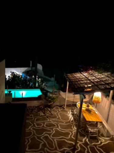 a patio with a table and a swimming pool at night at The Summer Pink House in Lachania