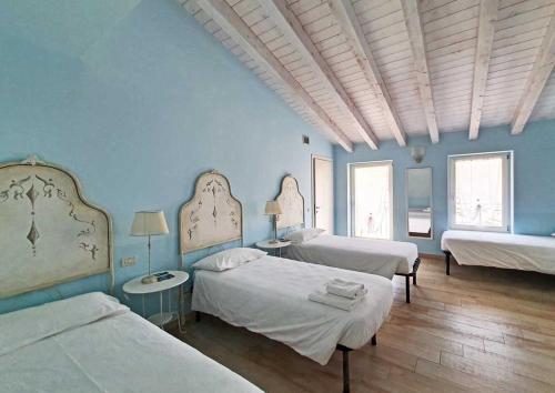 a bedroom with three beds and blue walls at Borgo alla Sorgente in Vallio Terme
