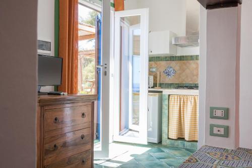 a kitchen with a door open to a kitchen with a television at Clelia Case Vista Mare in Ustica