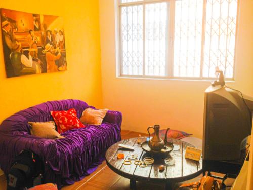 Una sala de estar con un sofá morado y una mesa. en Hostel da Providência, en Salvador