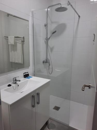 a white bathroom with a sink and a shower at Hotel Portugal in Lepe