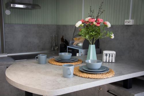 a kitchen table with two plates and a vase of flowers at Дом на берегу Новоладожского канала in Berezhnyye Lopatitsy