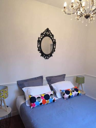 - une chambre dotée d'un lit bleu avec des oreillers et un miroir dans l'établissement Le 9 de Cour, Chambre Kiwi, à Carcassonne