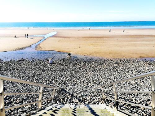 a beach with a fence and people on the beach at le Ti'Nid - Gîte de charme - Vue Mer in Langueux
