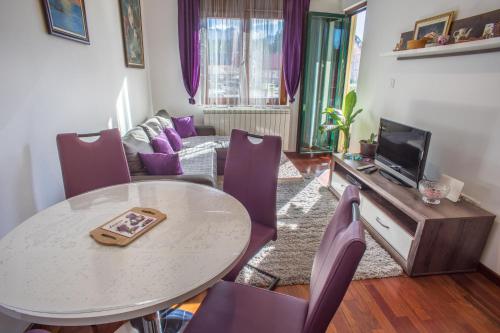 salon ze stołem i fioletowymi krzesłami w obiekcie GLORIA Apartman w mieście Žabljak