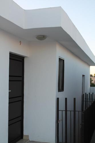 a white house with a black door and a fence at Hotel Bugambilias in Ciudad Obregón