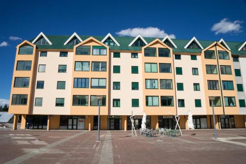 duży biały budynek z zielonym dachem w obiekcie GLORIA Apartman w mieście Žabljak