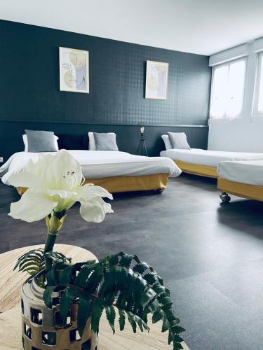 a room with two beds and a flower in a vase at Hotel Air-lane in Saint-Léger-sous-Brienne