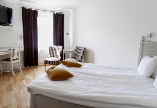 a bedroom with a large white bed with two pillows at Blommenhof Hotel in Nyköping