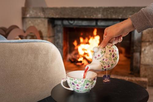 a person pouring tea from a tea pot into a cup at Hotel Alpina in Obertauern