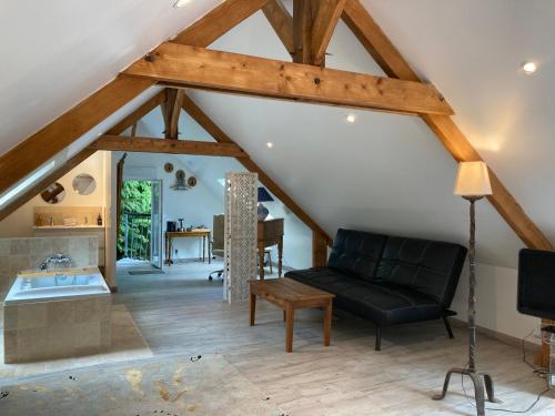 a living room with a black couch and a table at A 2 heures de Paris, Loft Romantique de 55 m2 en pleine nature entre campagne et mer in Saint-Philbert-des-Champs